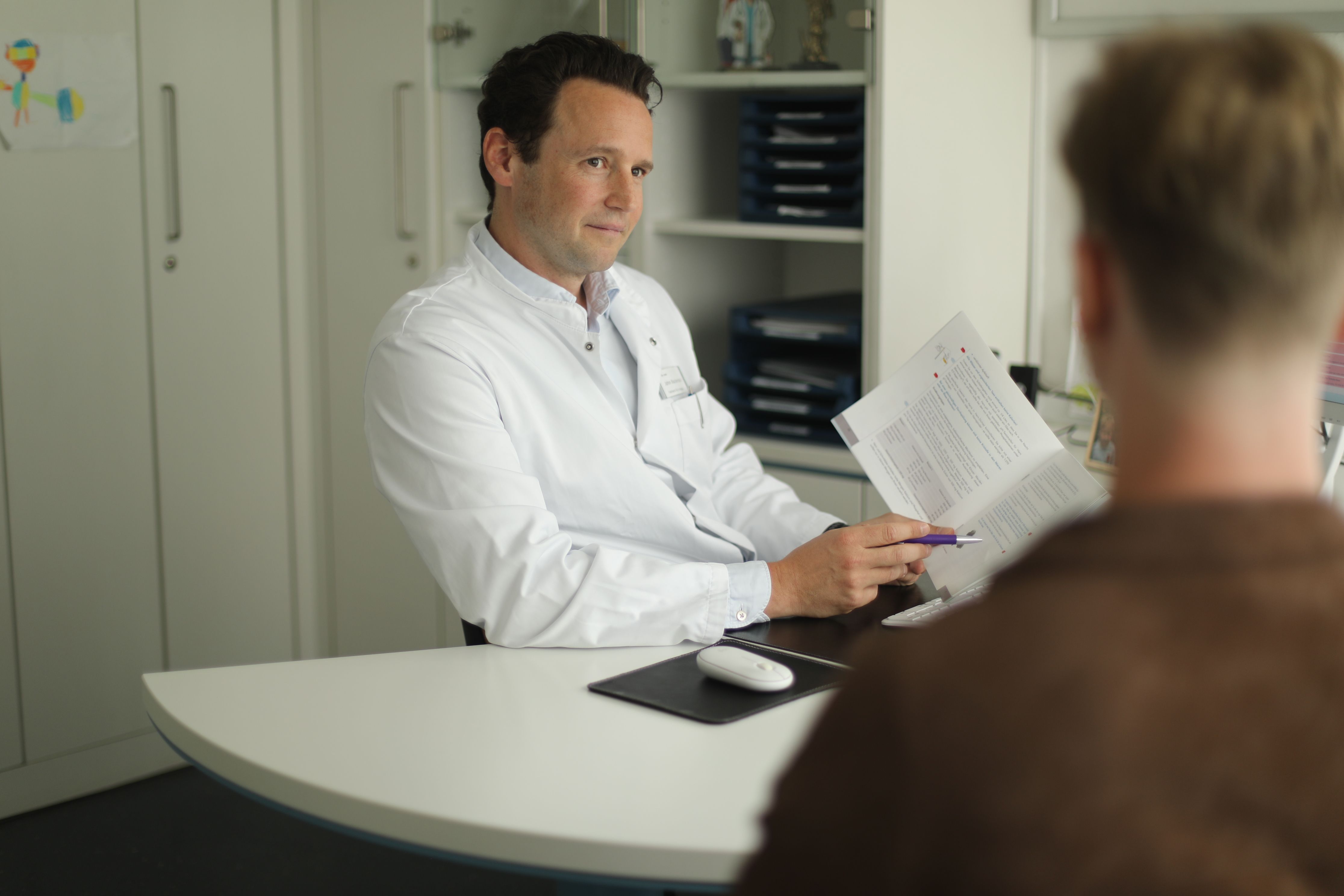 Urologe bespricht Befundunterlagen mit einem Patienten im Sprechzimmer
