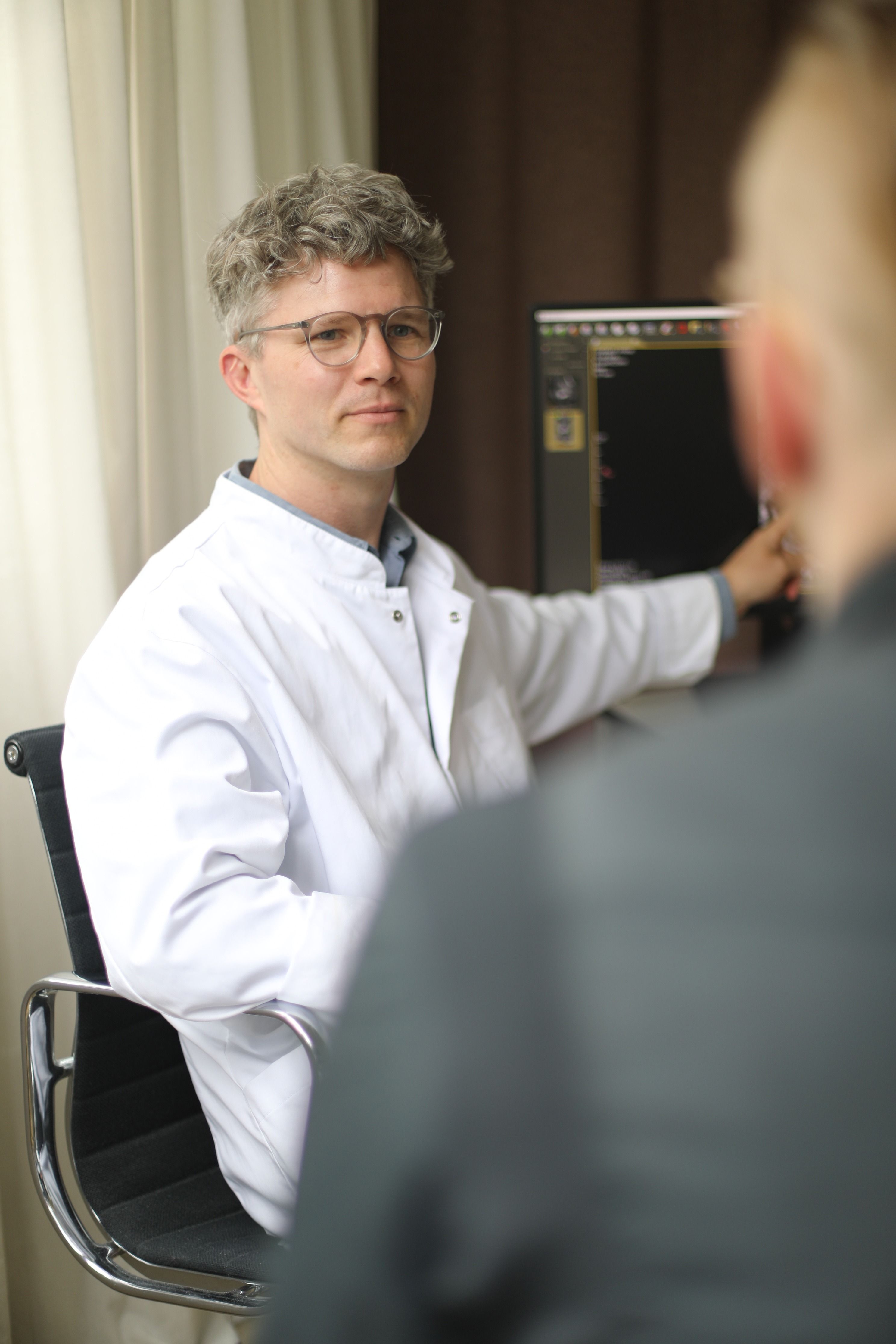 Urologe erläutert einem Patienten im Beratungsgespräch Befunde am Bildschirm